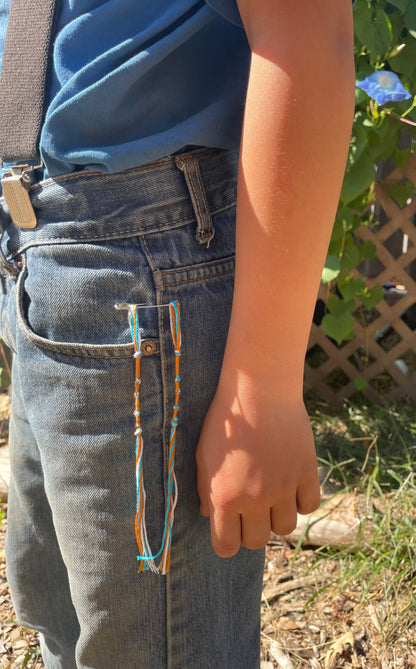 Set of four brown and blue tzit-zit tassels with blue cord attached to jeans for sizing referance by The Family of Yah