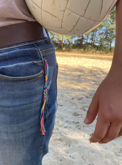 Hand-woven 100% cotton multi-colored tassels display up close on jeans by The Family of Yah
